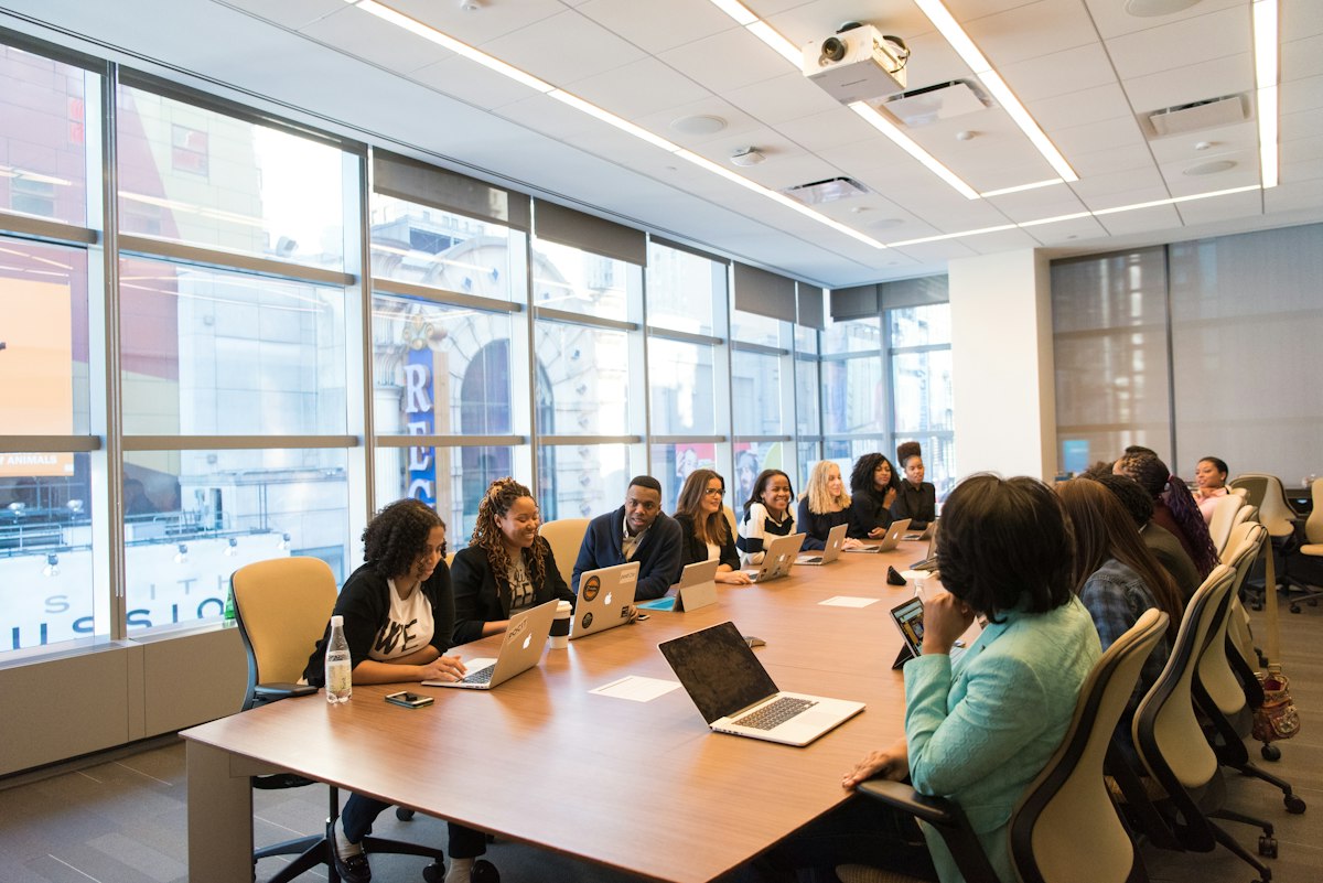 A team of colleagues meeting around a table with laptops