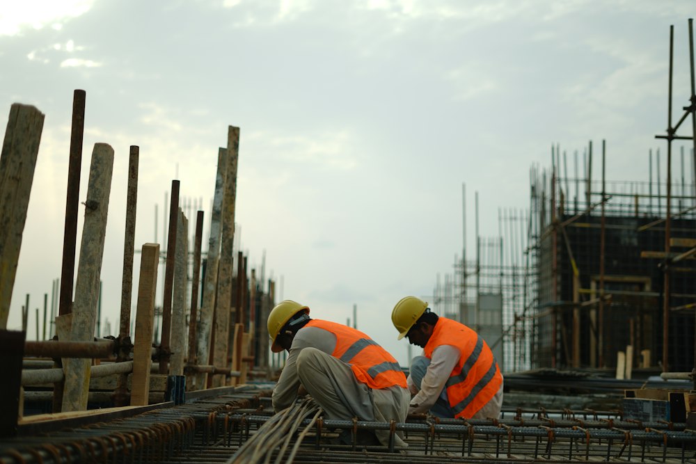 Construction workers in hard hats tying rebar on a building site