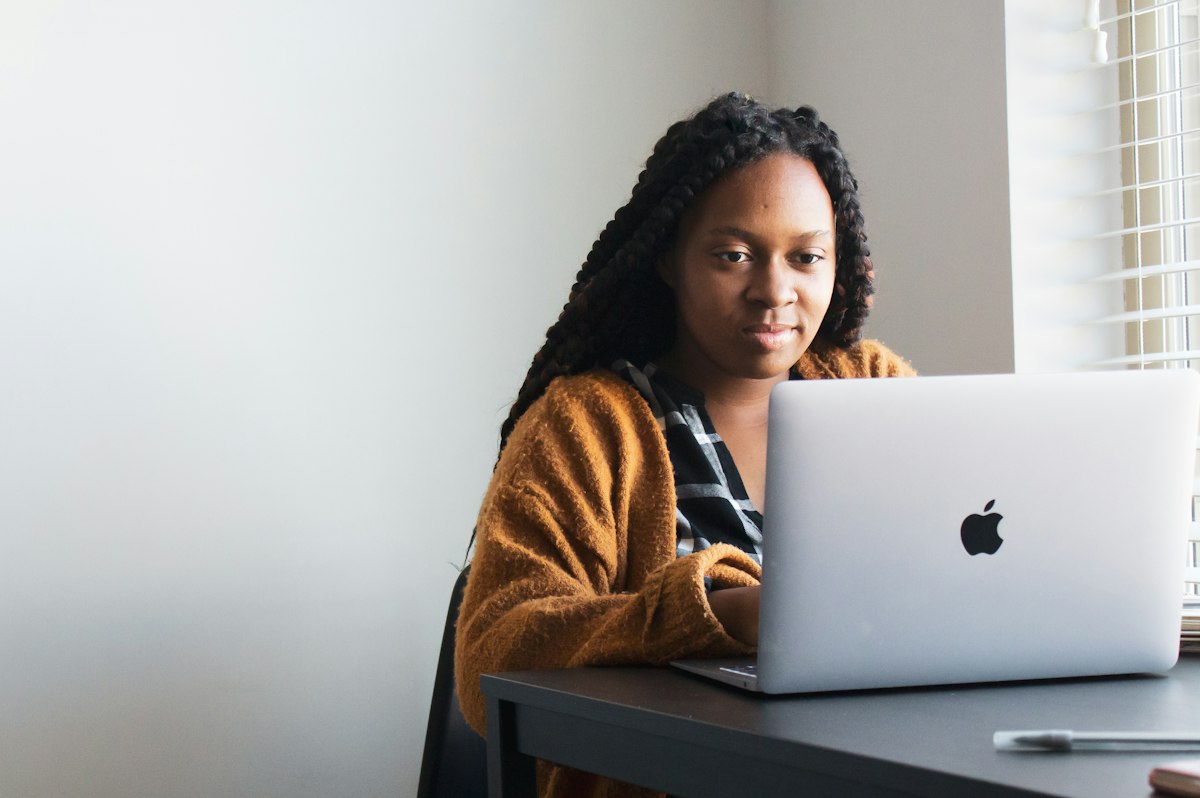 A woman working on a laptop at a bright desk