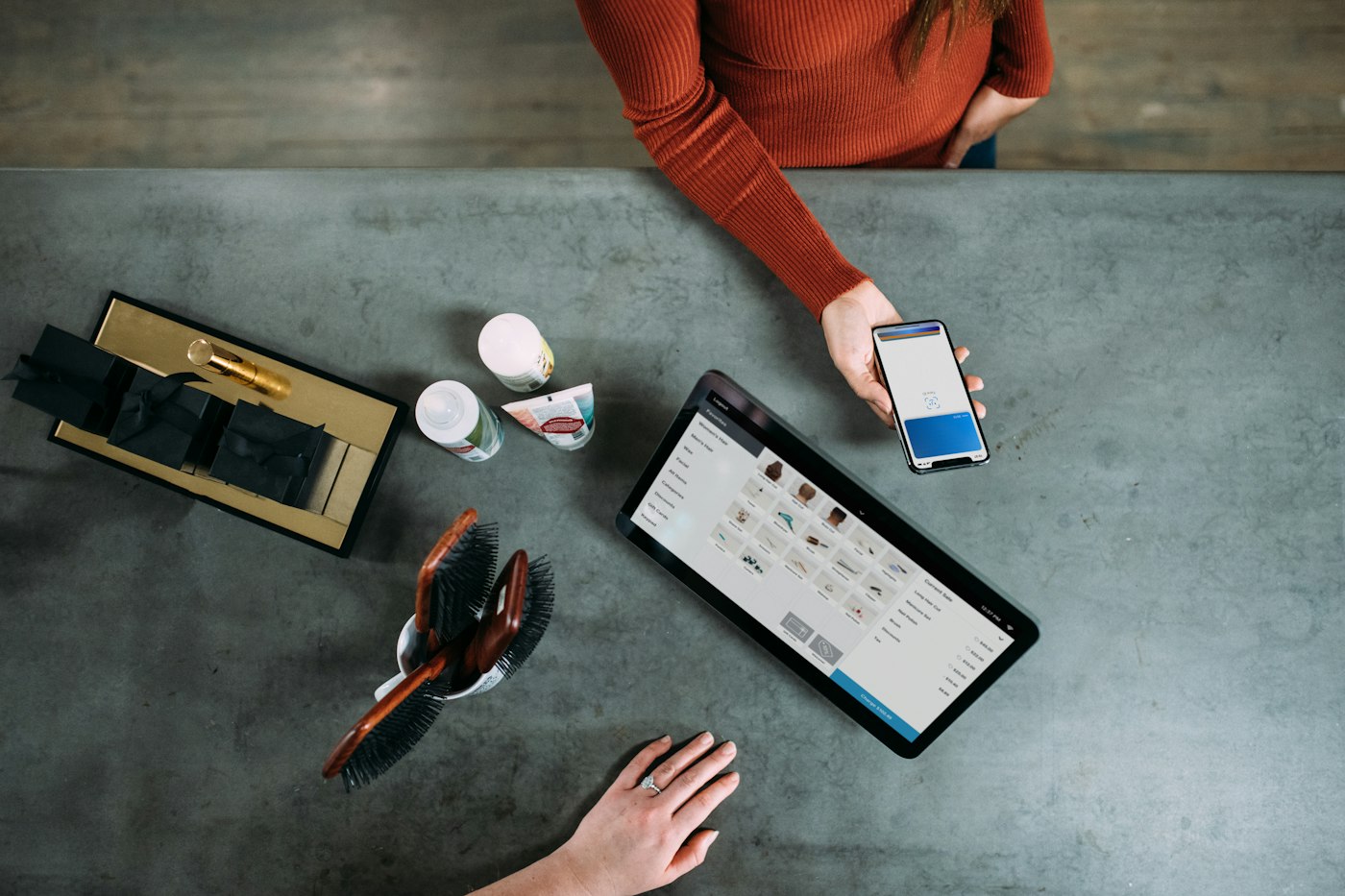 A customer paying by phone at a counter beside a tablet till