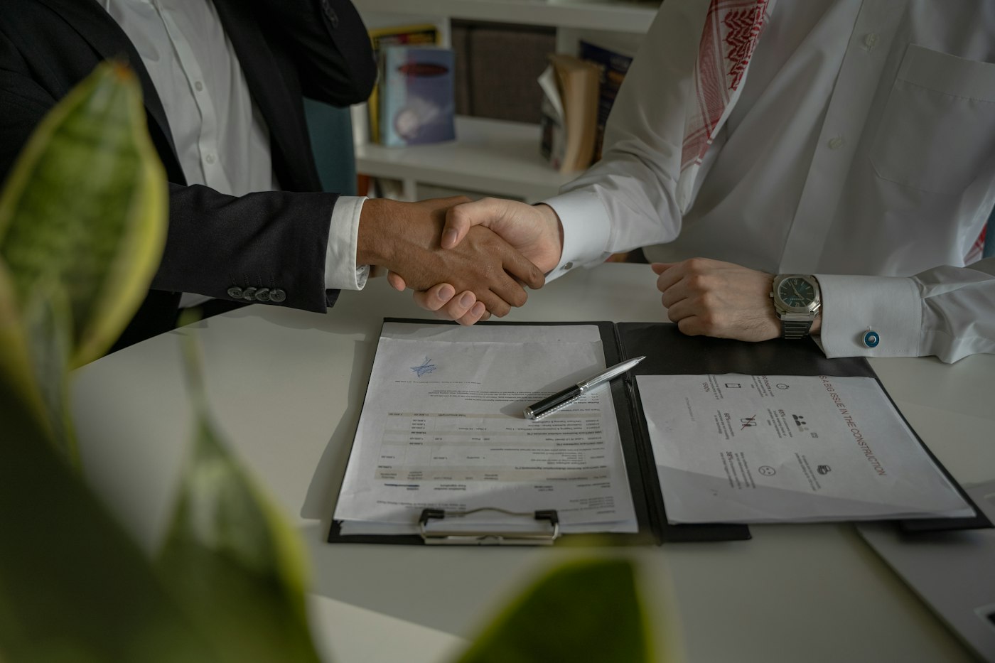 Two people shaking hands over signed supplier documents