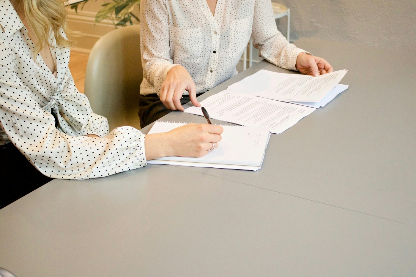 A woman signing a document while a colleague waits to review it
