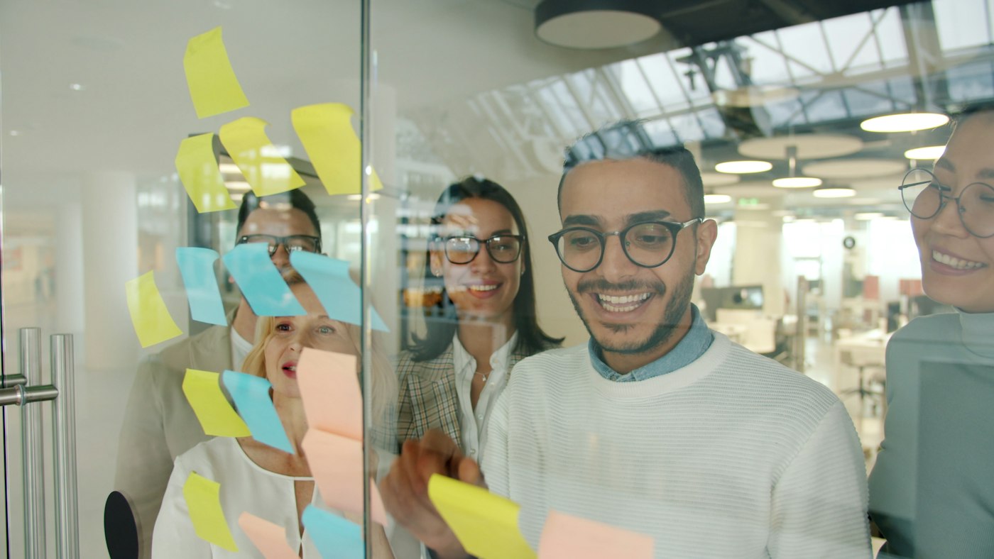 A team planning work with sticky notes on a glass wall