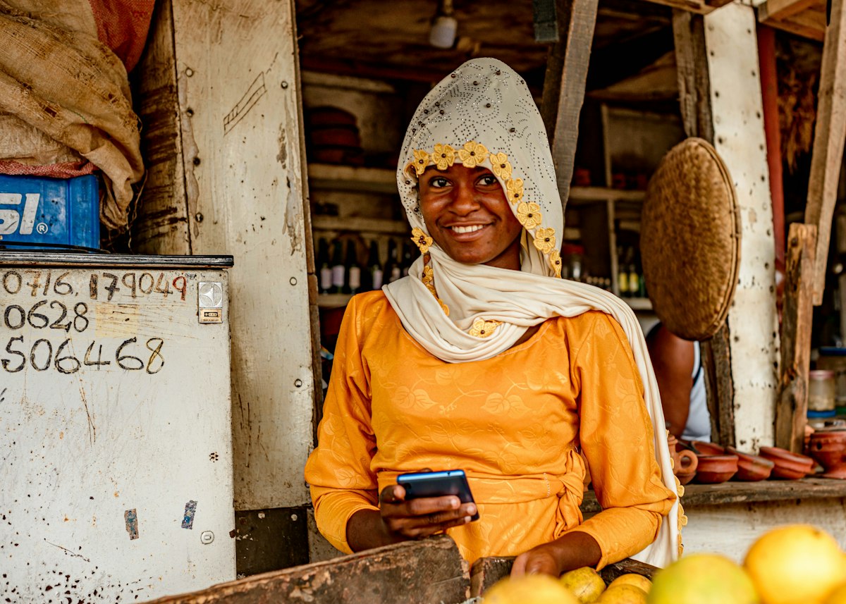 A market trader at her fruit stall checking her phone