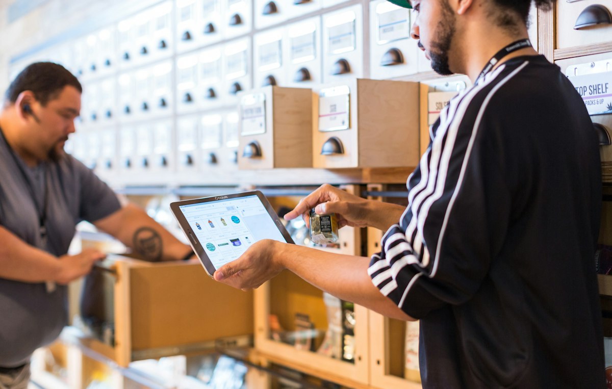 Two colleagues in a stockroom checking orders on a tablet