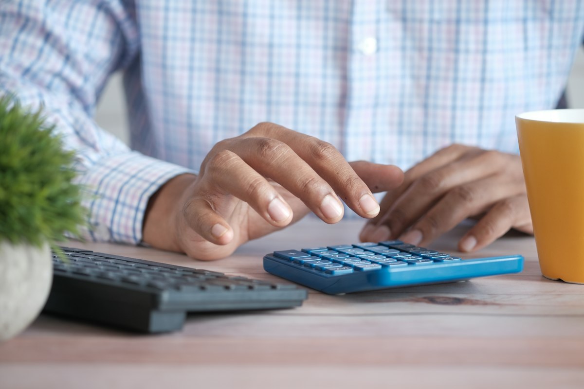 An accountant working through figures on a computer with a calculator